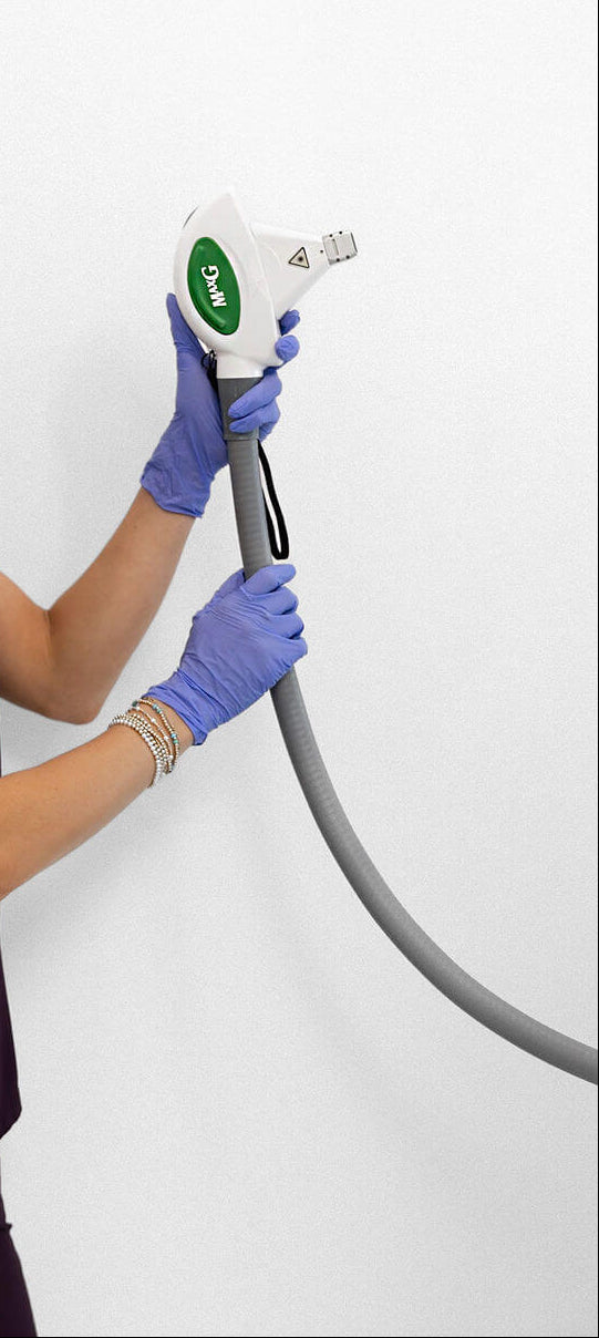 Person in purple scrubs holding a medical device against a white background