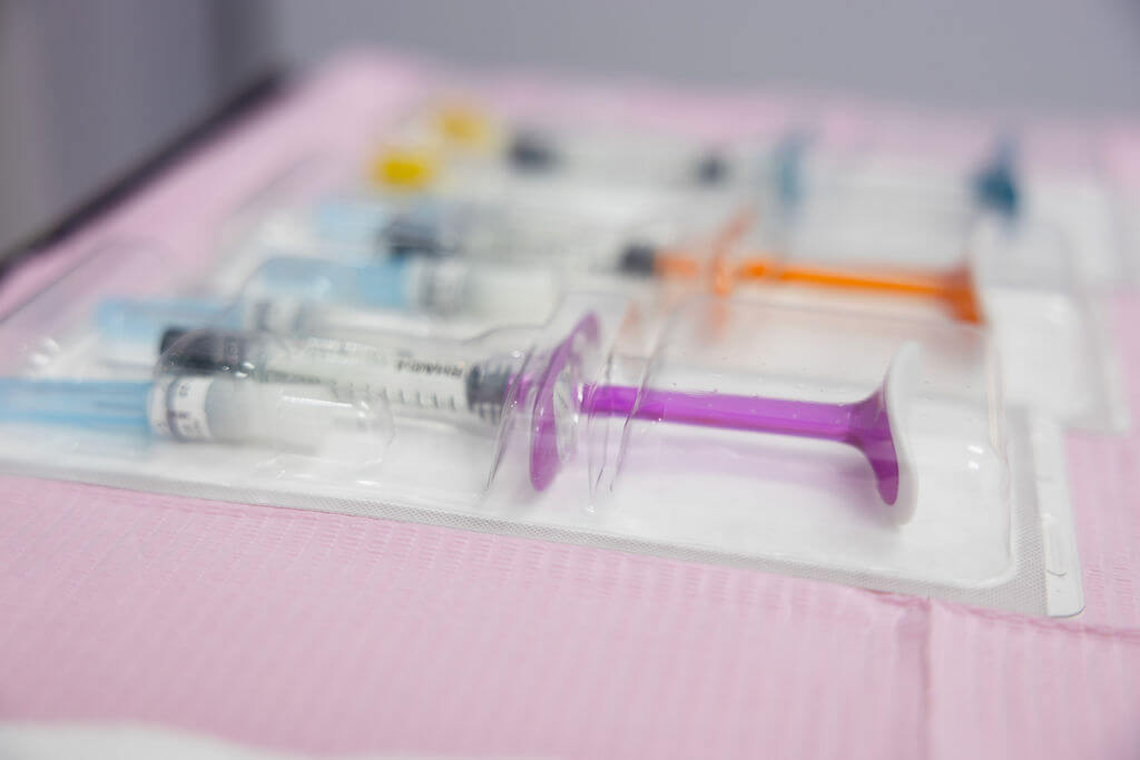 Medical syringes in packaging on a pink surface